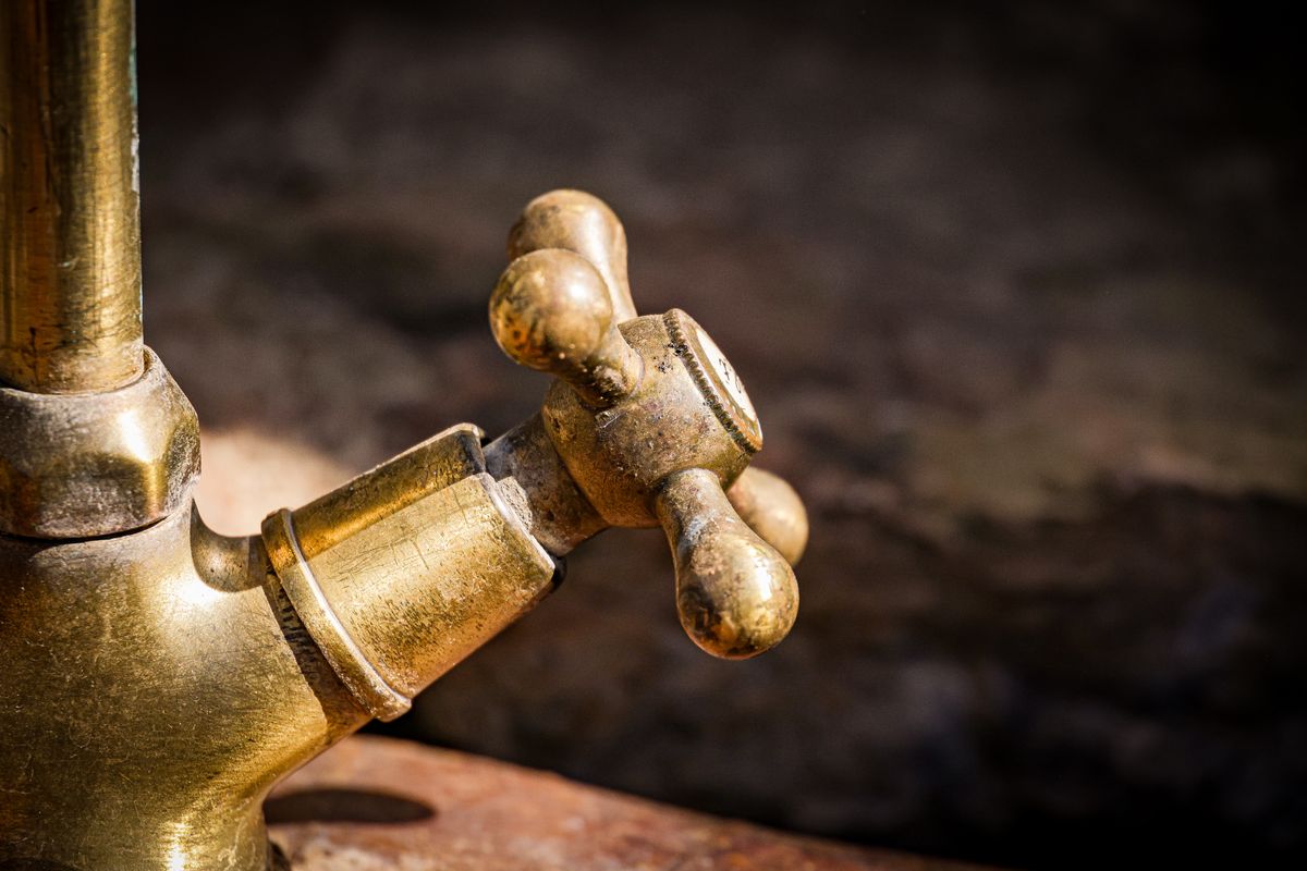 Aged brass tap handle showing surface corrosion, an early visible sign of aggressive water
