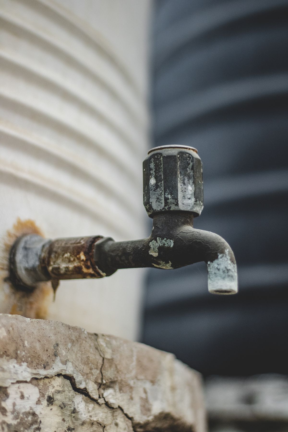 Weathered outdoor tap heavily stained with rust, the orange discolouration that indicates iron rather than ordinary salt residue