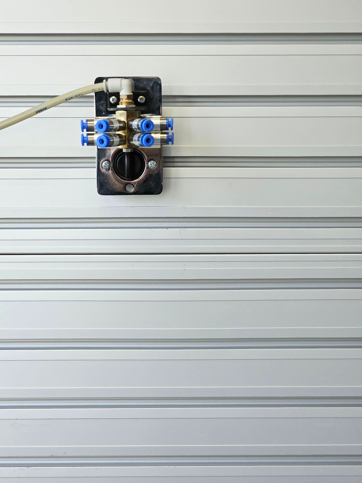 Wall-mounted valve with its handle on a run of metal pipes, the type of manual bypass arrangement that routes water around a softener and starts leaking when its seals dry out