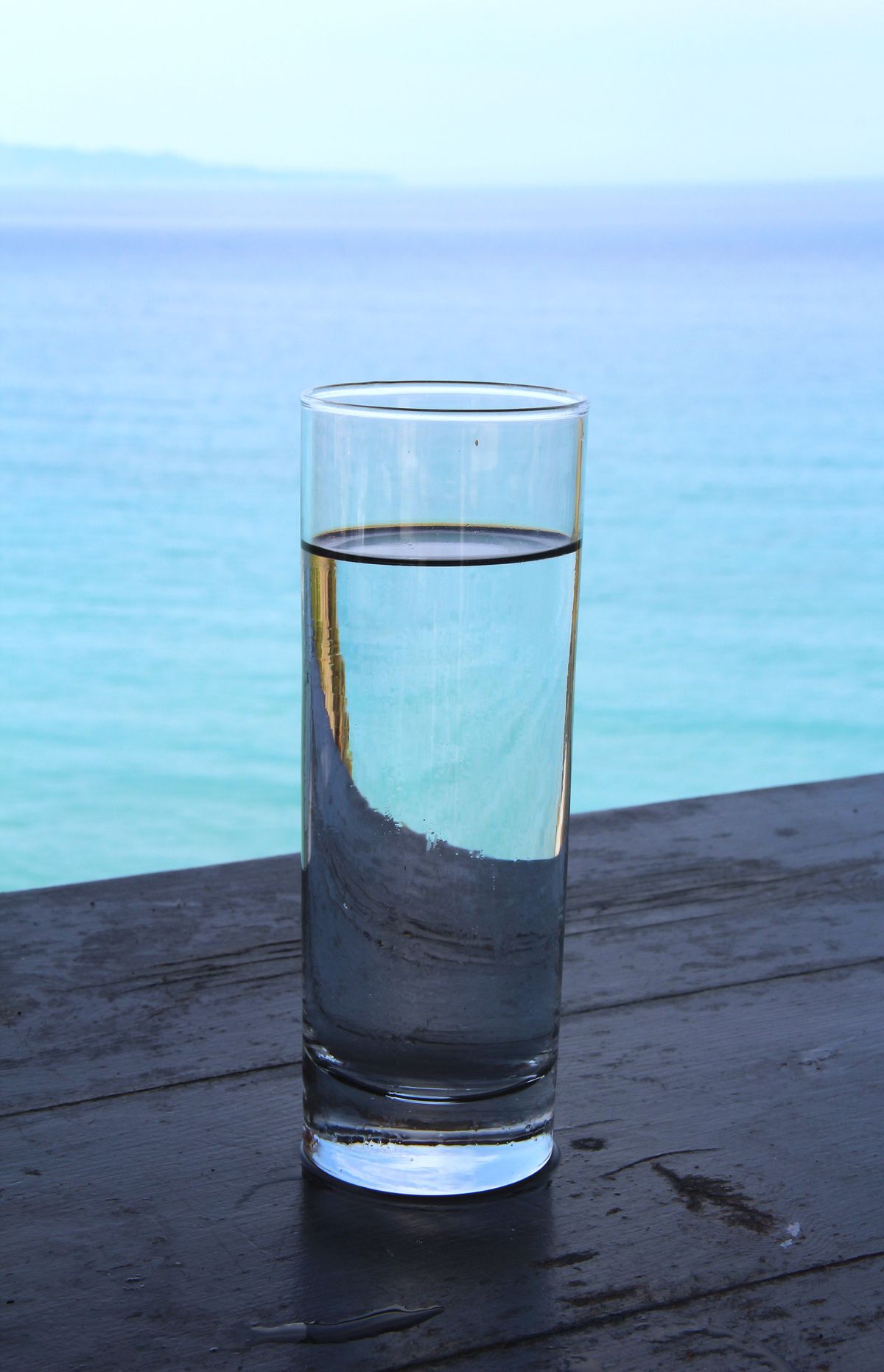 Tall glass of clear drinking water on a wooden table, the taste test that starts a salty softened water diagnosis