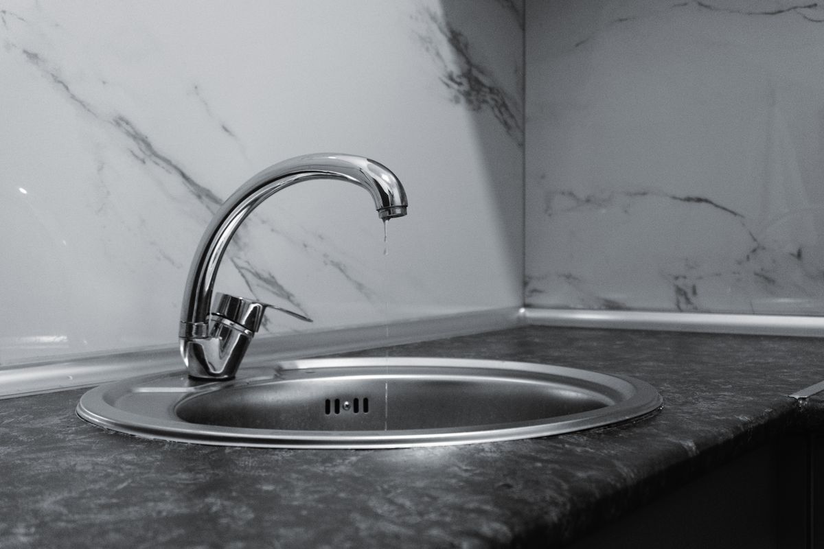 Chrome kitchen tap with water beading at the spout, the fixture most people wrongly test first when checking a water softener