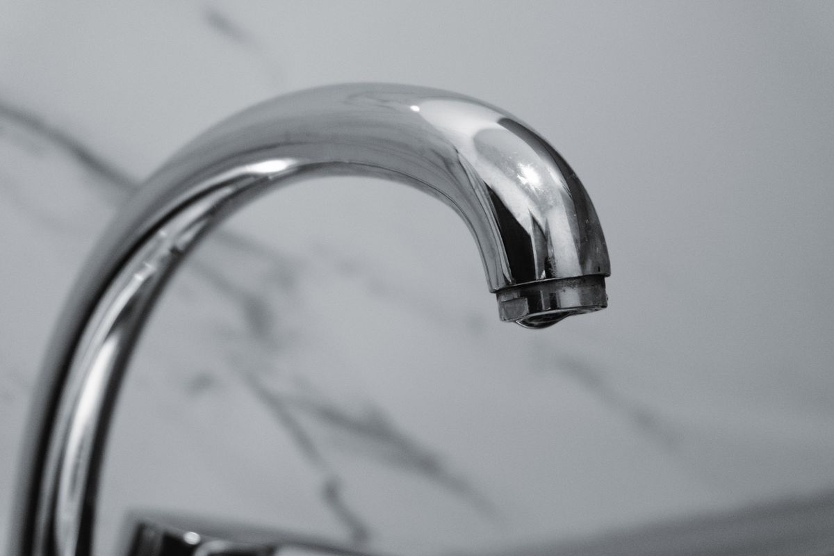 Close-up of a chrome faucet spout and aerator tip, where scale flakes can contaminate a hardness sample