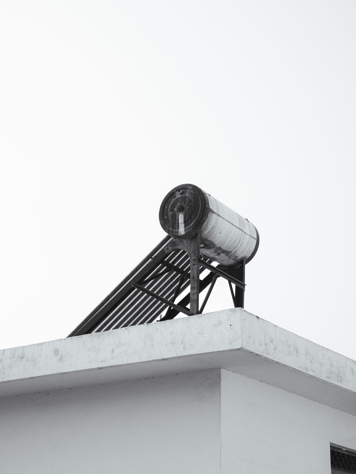 Solar water heater on a rooftop against a clear sky, a reminder that heater type changes the scale calculus