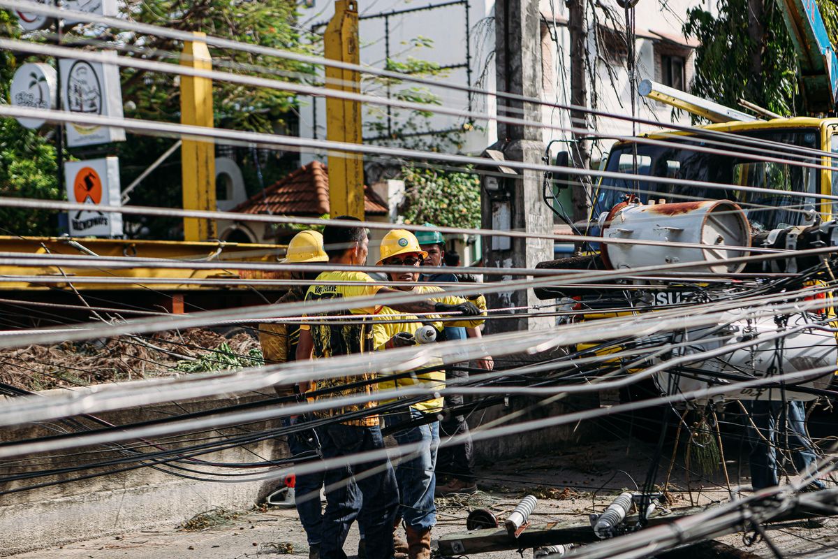 Utility crew repairing downed power lines on a street, the kind of outage a non-electric Kinetico softener keeps working through