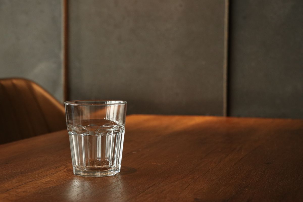 Clear glass of water standing on a wooden table, the setup for the 24-hour glass test that tells tannin colour from iron