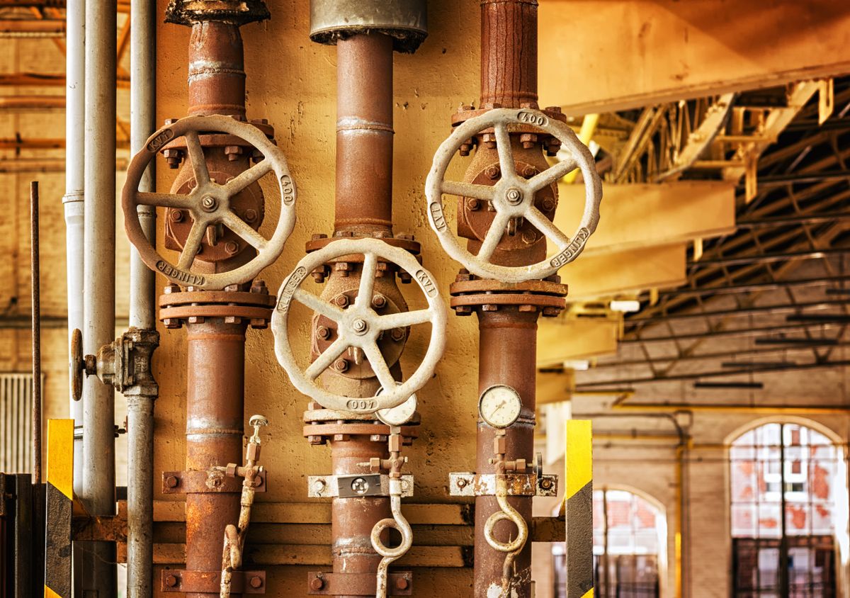 Close-up of corroded industrial pipes and valves covered in orange rust, the same ferric iron deposit that coats softener resin beads and responds to a reducing cleaner