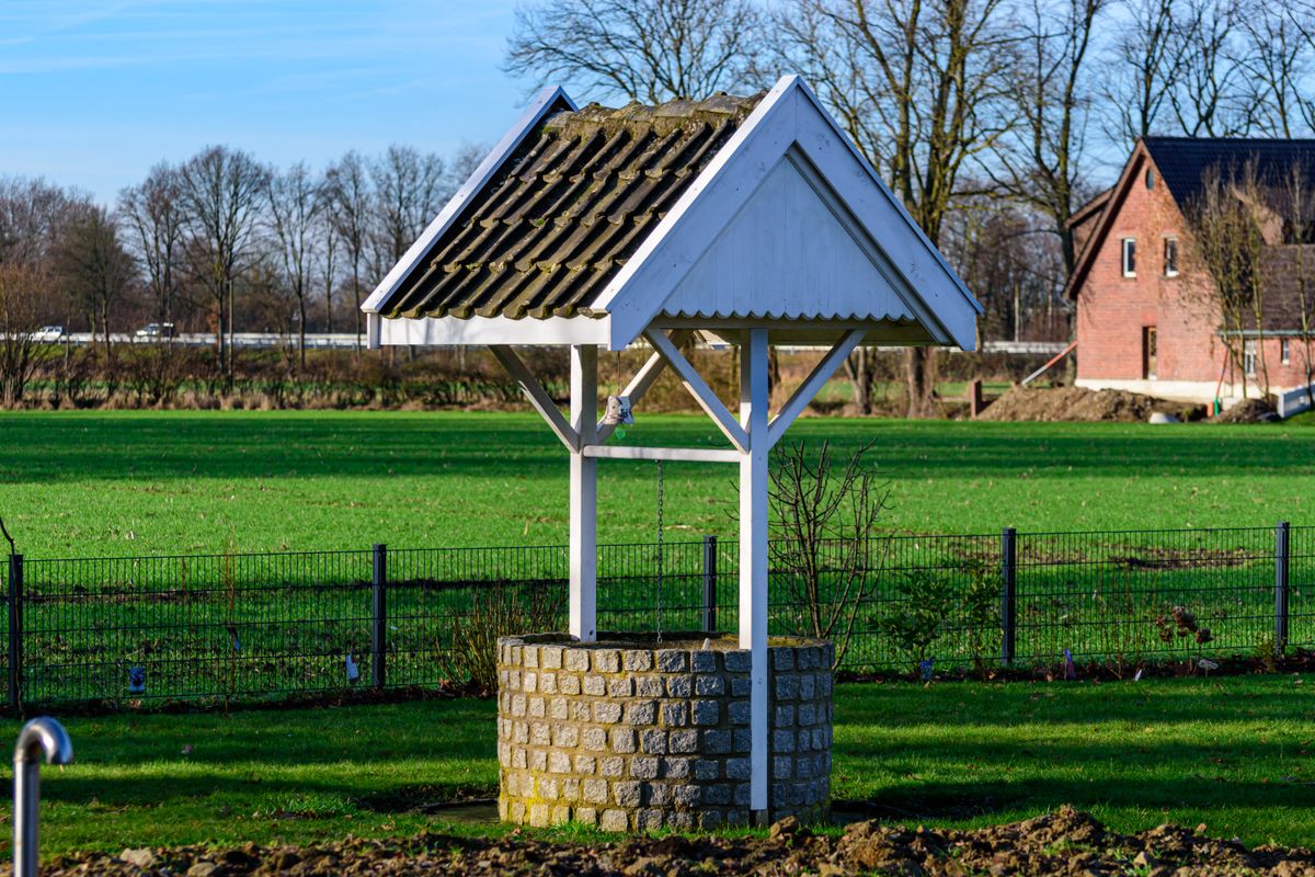 Traditional stone water well with a wooden roof in a rural landscape, illustrating why well water is hard