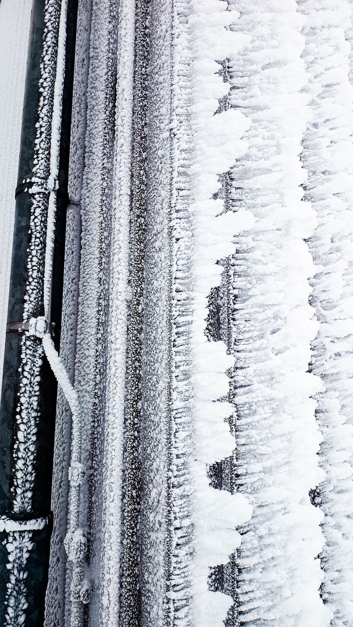 Close-up of frost-covered pipes in winter, the conditions in which water trapped in a softener's valve and bypass freezes and expands