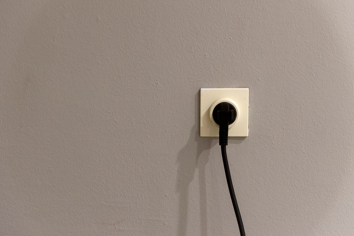 Black power plug inserted into a white wall socket, the connection that should only be pulled after a stuck softener has been put into bypass