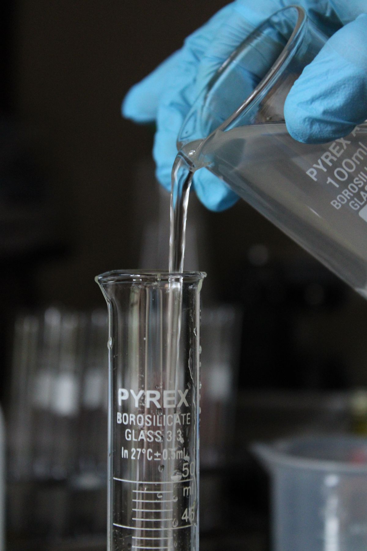 Scientist pouring a liquid sample into a beaker, the kind of bench testing used to measure resin cross-link degradation