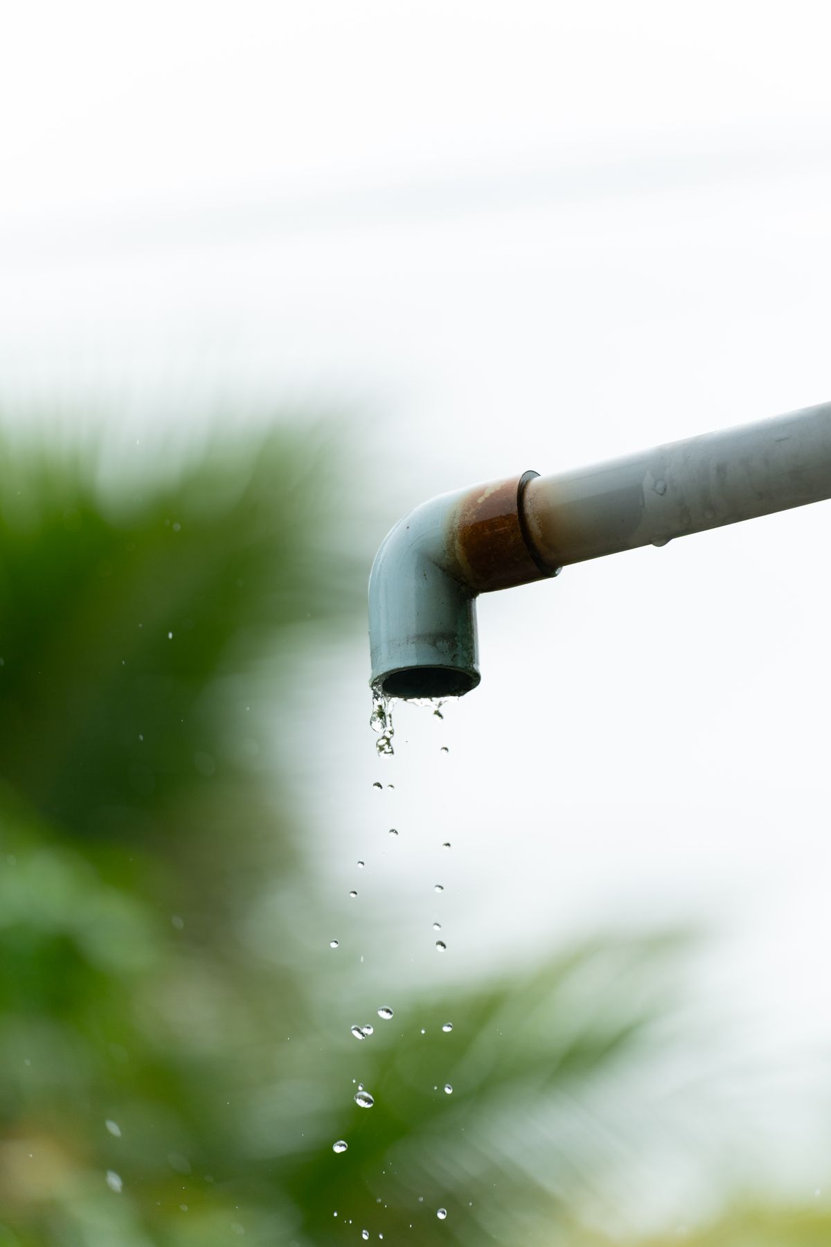 Water droplets falling from a rusted outdoor pipe, the staining pattern that indicates iron in a system rather than ordinary mineral residue