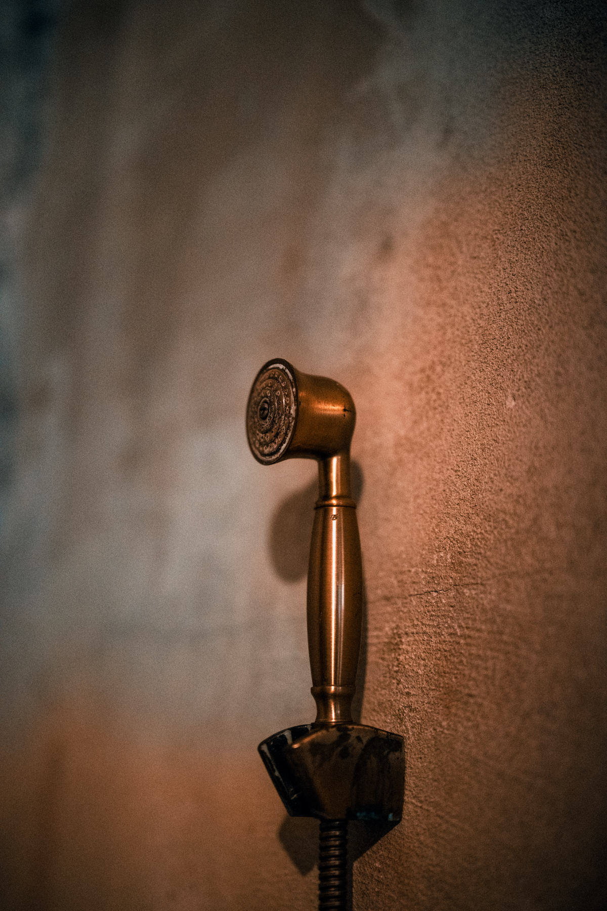 Close-up of a vintage brass shower head mounted on a textured wall