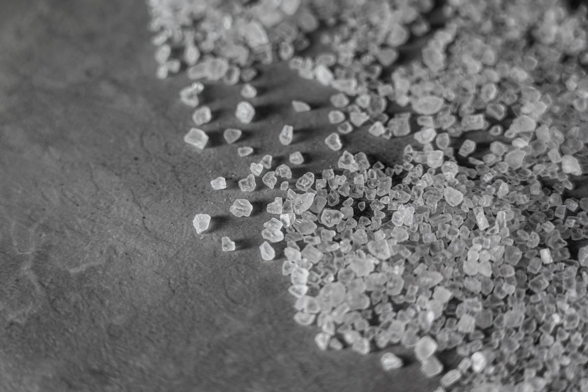 Black and white close-up of coarse rock salt granules, the grade of softener salt most likely to leave insoluble grit behind in a brine injector