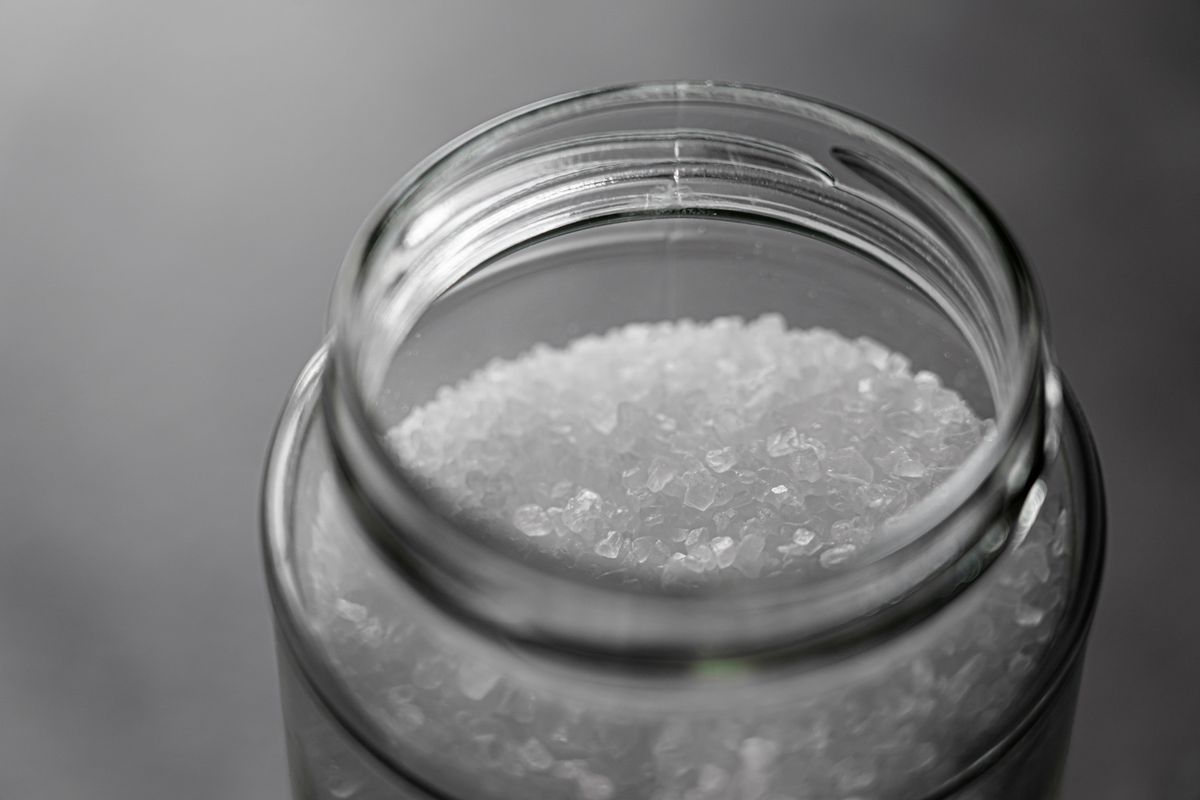 Coarse salt crystals in a glass jar, the consumable a softener needs available and loose to regenerate