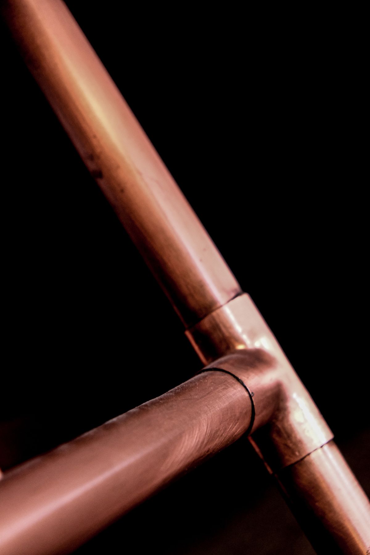 Close-up of copper plumbing pipes, the material most at risk when pH and water hardness are interpreted separately
