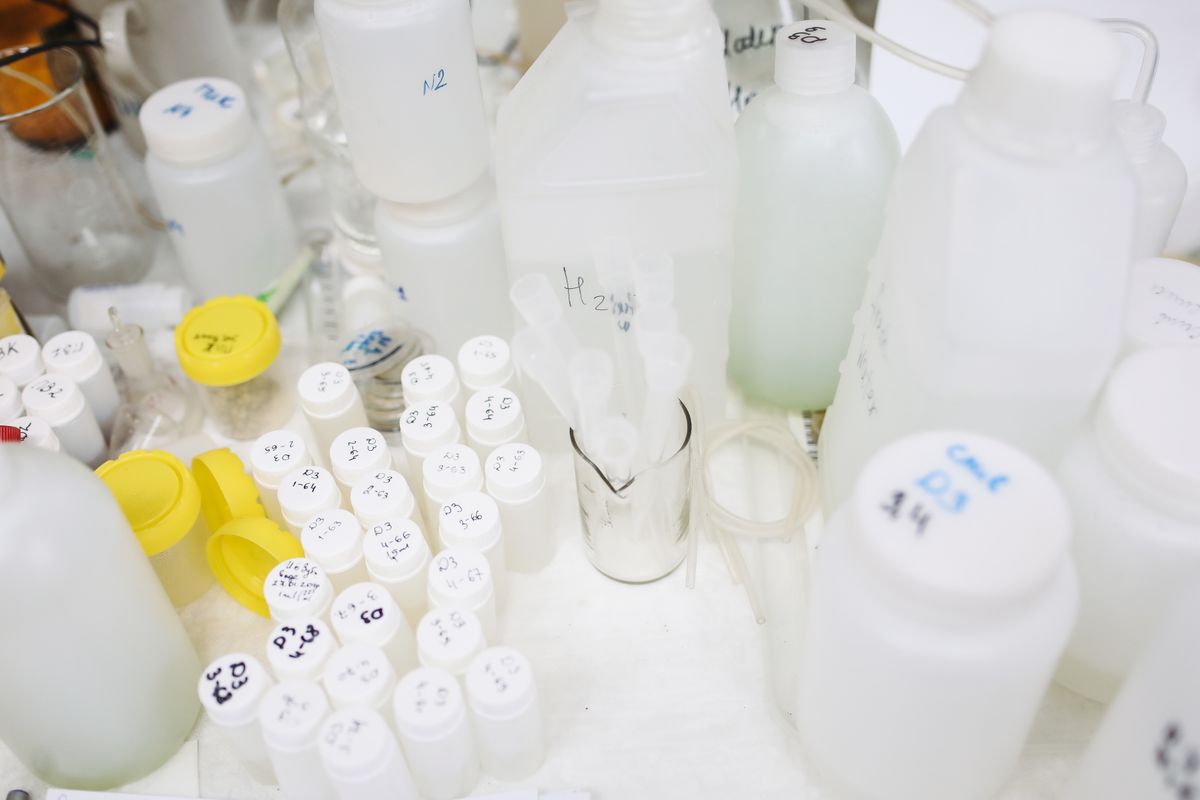 Sample bottles and small vials with coloured caps on a laboratory bench, the kind of full-panel well water analysis to order before choosing a softener