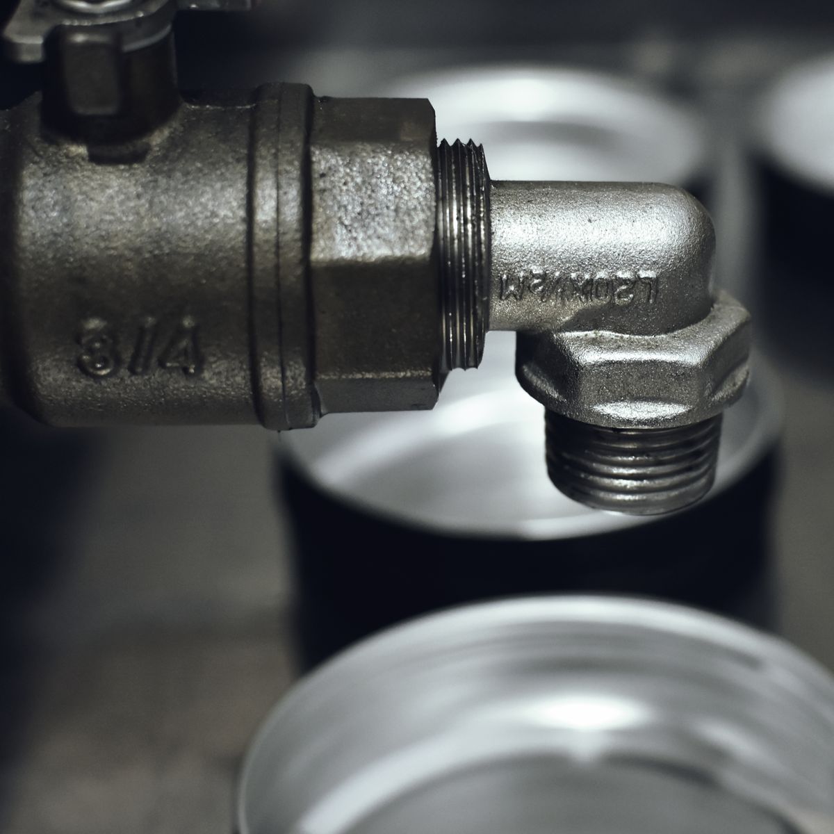 Rugged metal pipe fitting in an industrial setting, the kind of rigid joint where a water hammer pressure wave reflects and makes pipes bang
