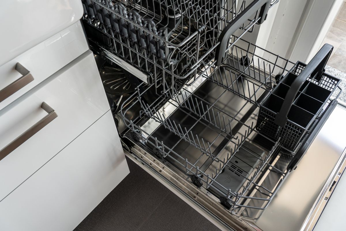 Open stainless steel dishwasher with empty racks, ready to be reset with new dishwasher settings for soft water