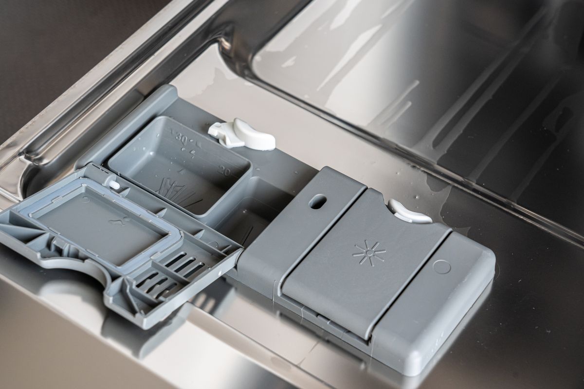 Dishwasher detergent dispenser with the main cup open beside the closed rinse aid compartment