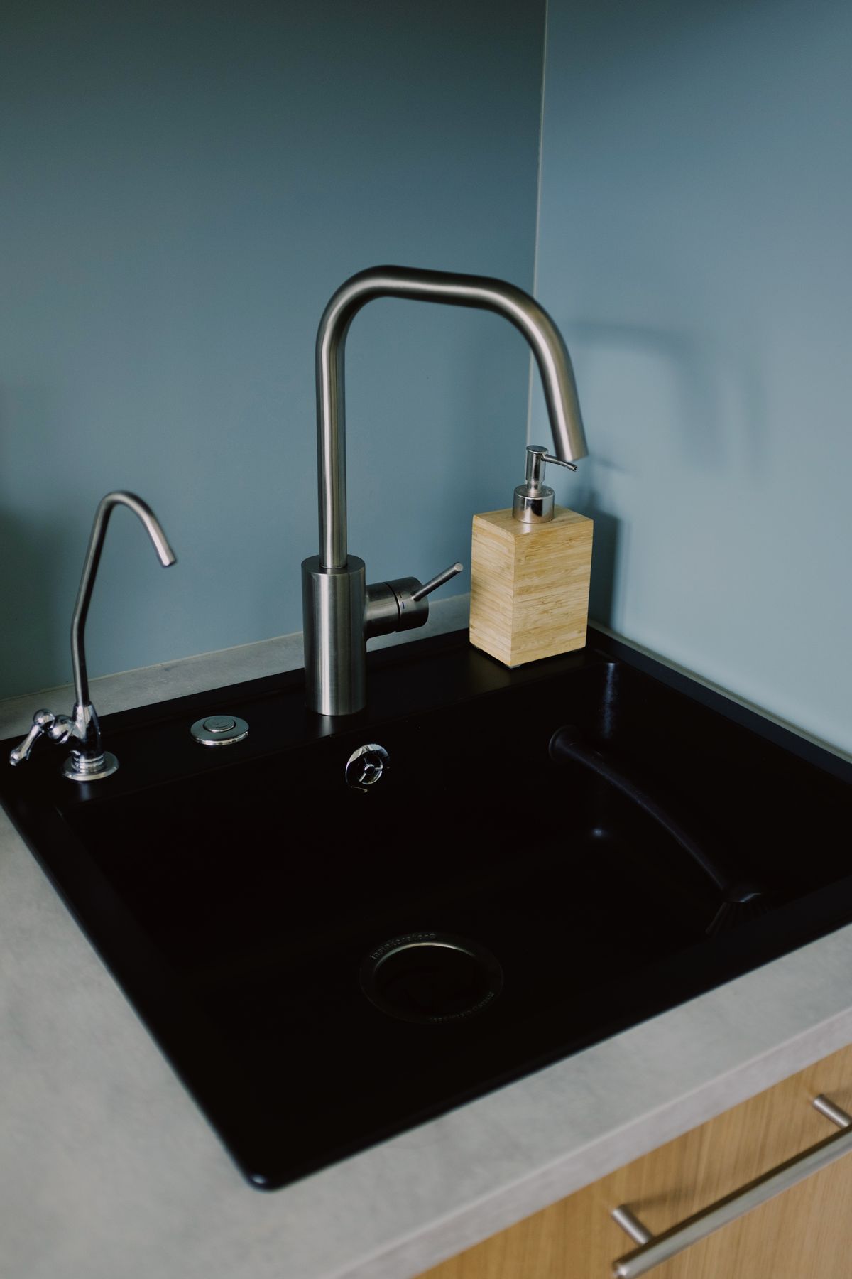 Black kitchen sink with a slim dedicated drinking water faucet mounted beside the main stainless steel tap, the layout a tankless RO system uses