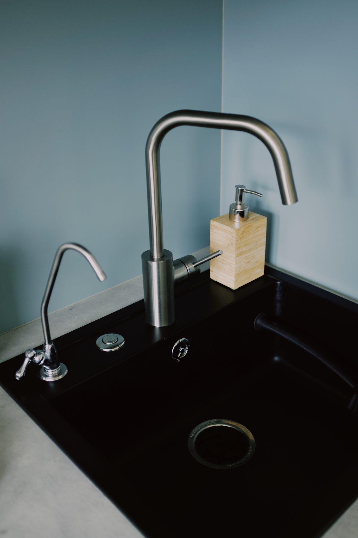 Black kitchen sink with a slim dedicated drinking water faucet mounted beside the main stainless steel tap