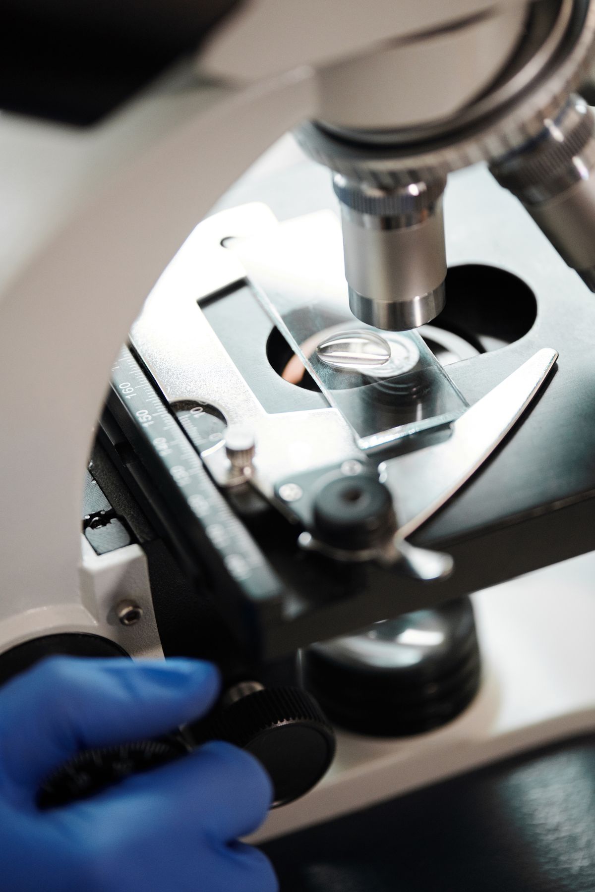 Close-up of a microscope positioned over a prepared slide, the level of inspection used to judge whether resin beads have lost structure