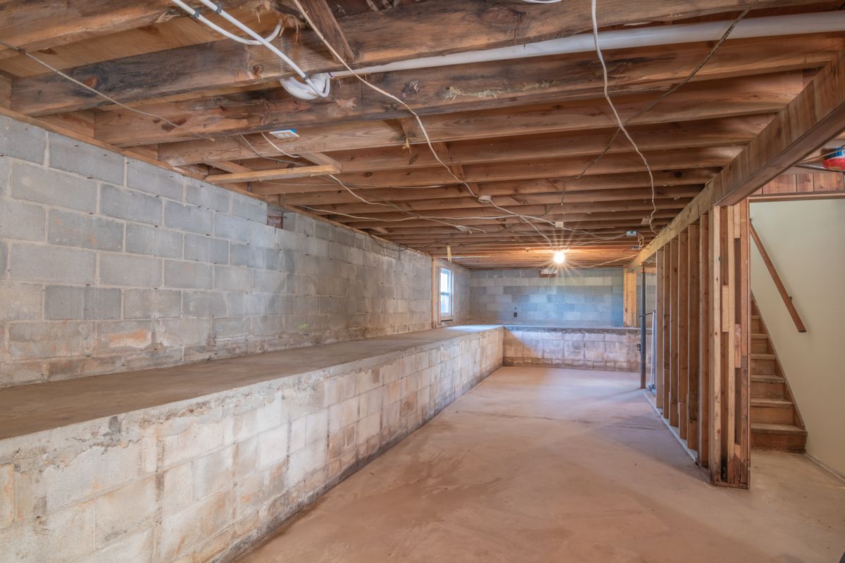 Unfinished basement with concrete block walls, exposed joists and a concrete floor; a softener installed below grade often has to lift its drain water