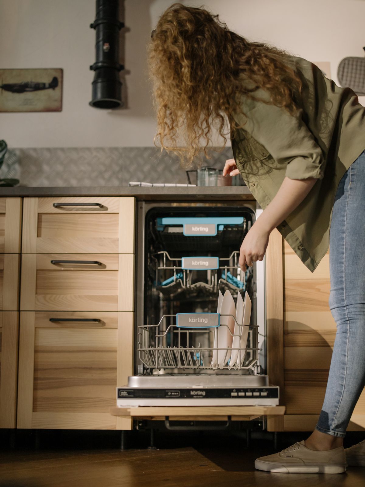 Person loading dishes into an automatic dishwasher, the load worth hardness-testing before diagnosing residue