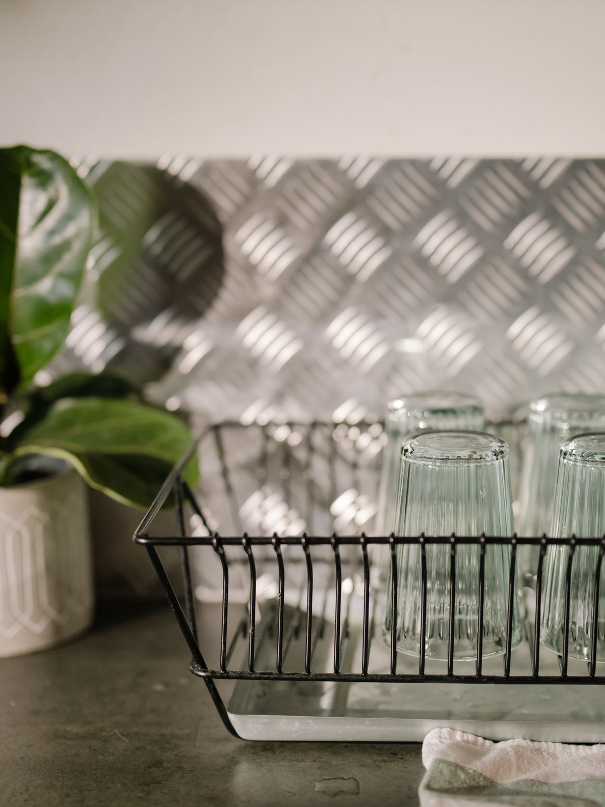 Clear drinking glasses drying upside down in a wire dish rack. Spot-free glassware on hard water needs softening, not a salt-free conditioner