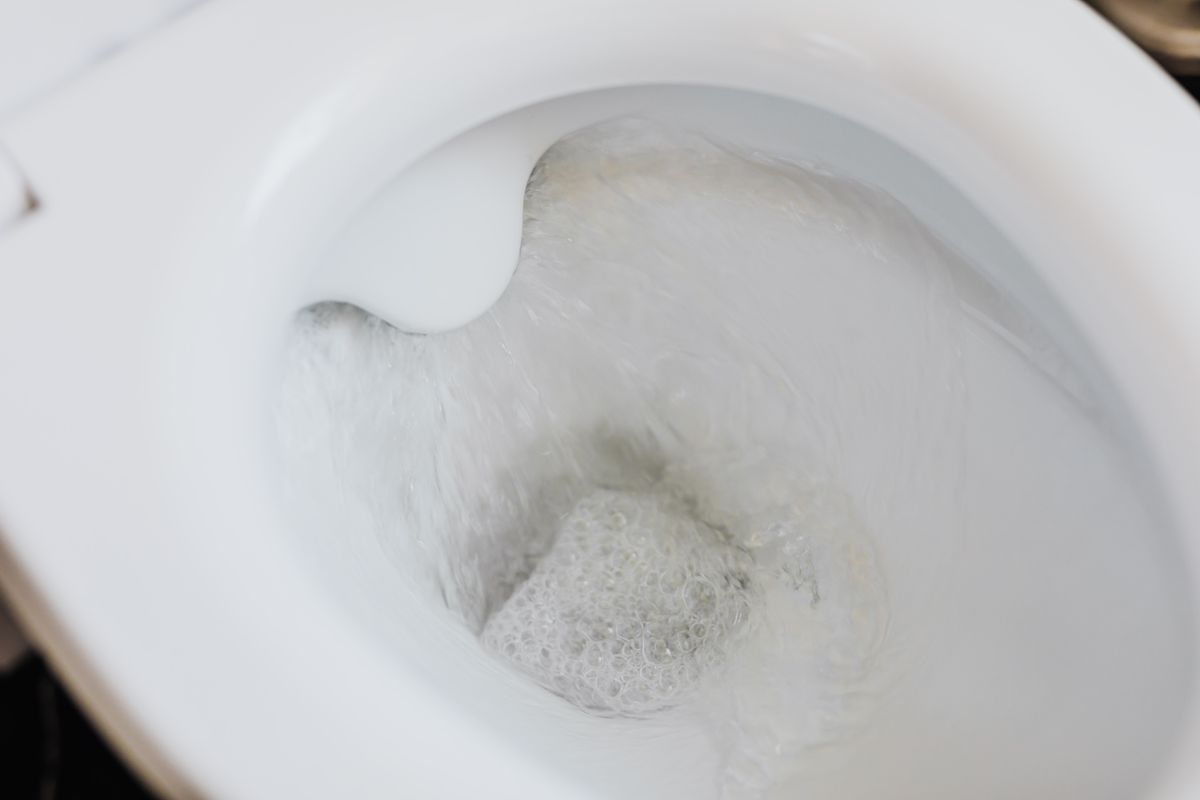 Clean white ceramic toilet bowl with water flushing through it