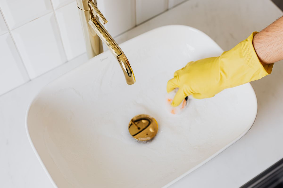 Sponge and detergent being used on a sink, the source of the soap film often mistaken for scale on softened water