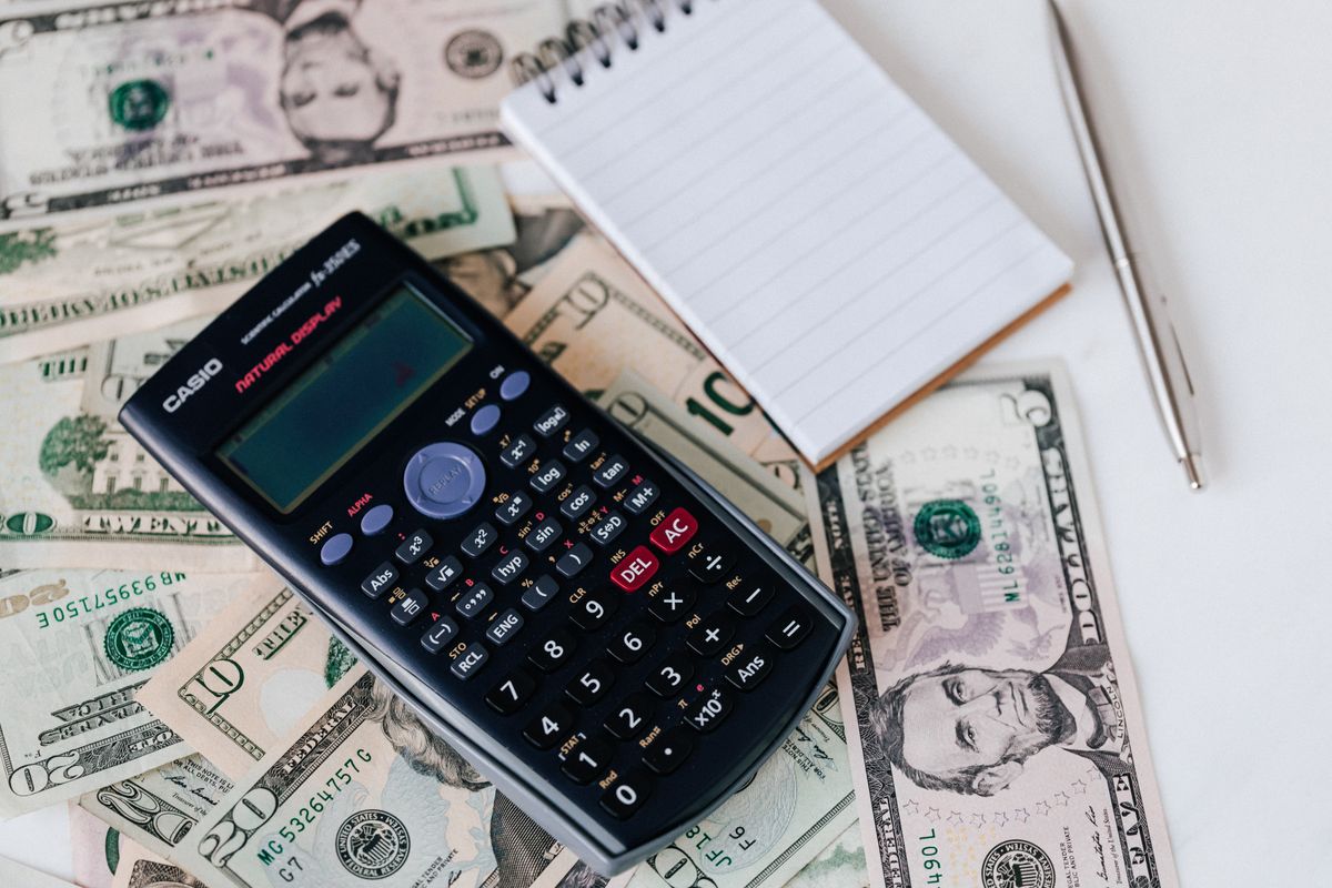 Calculator and notepad resting on United States dollar bills, the cost comparison between re-bedding a softener and replacing the unit