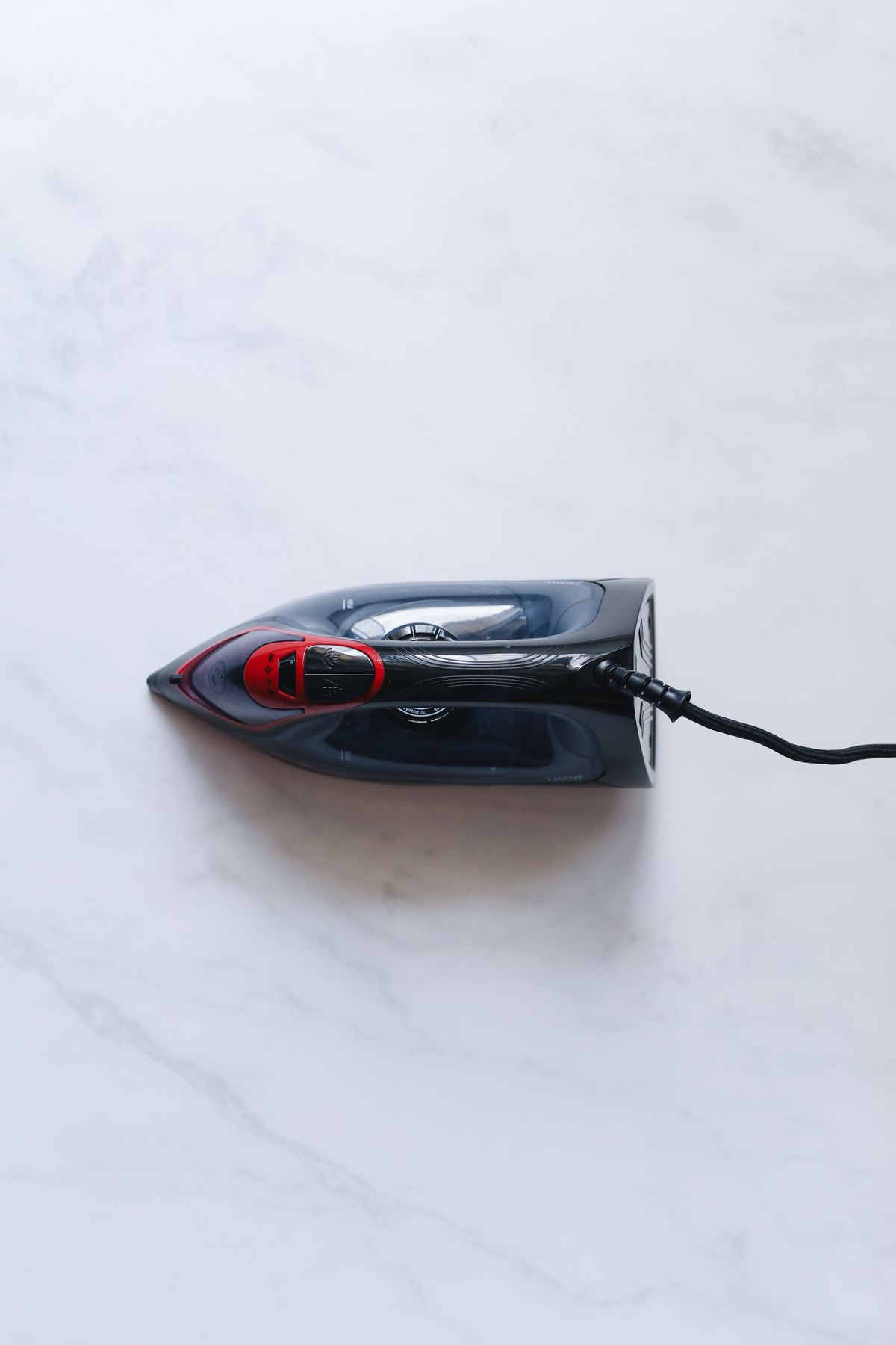 Modern electric steam iron seen from above on a marble surface
