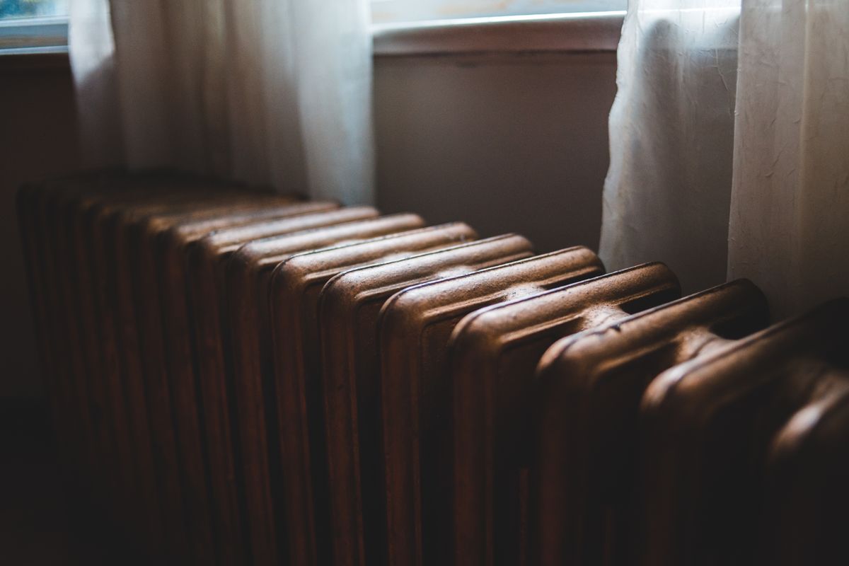 Dark cast iron radiator under a window, part of a sealed hydronic loop where softened water in a boiler needs inhibitor