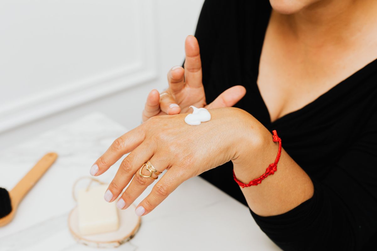 Woman applying moisturising cream to her hands, the response most people rely on regardless of water treatment