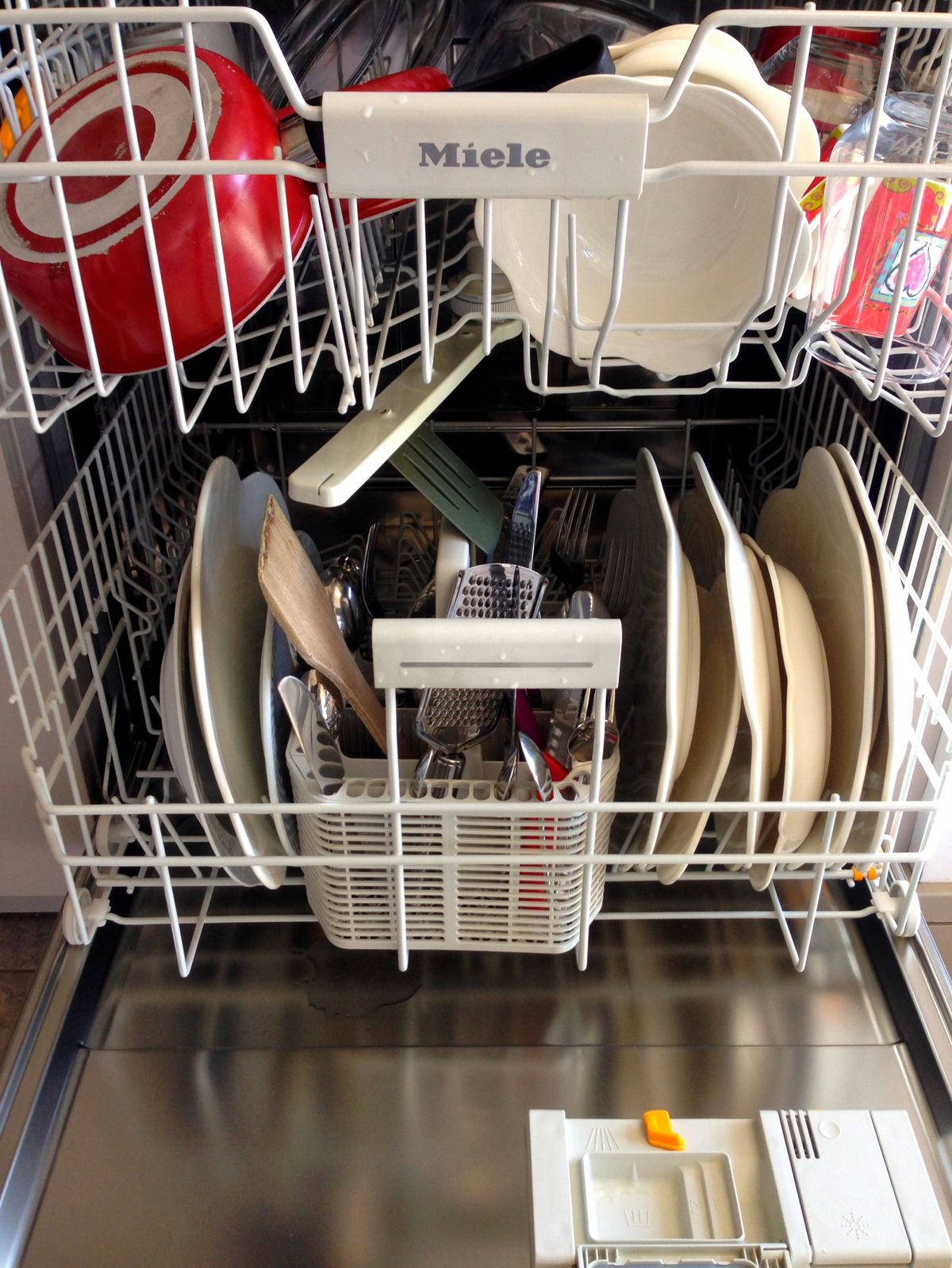 Open dishwasher loaded with clean plates and bowls where a dishwasher white film on dishes would show