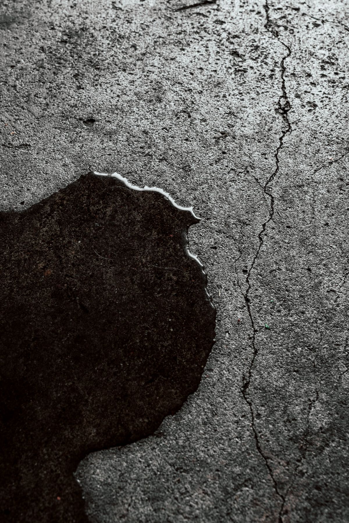 Wet, cracked concrete floor surface with standing moisture, showing why a brine tank overflow fitting needs its own line to a drain