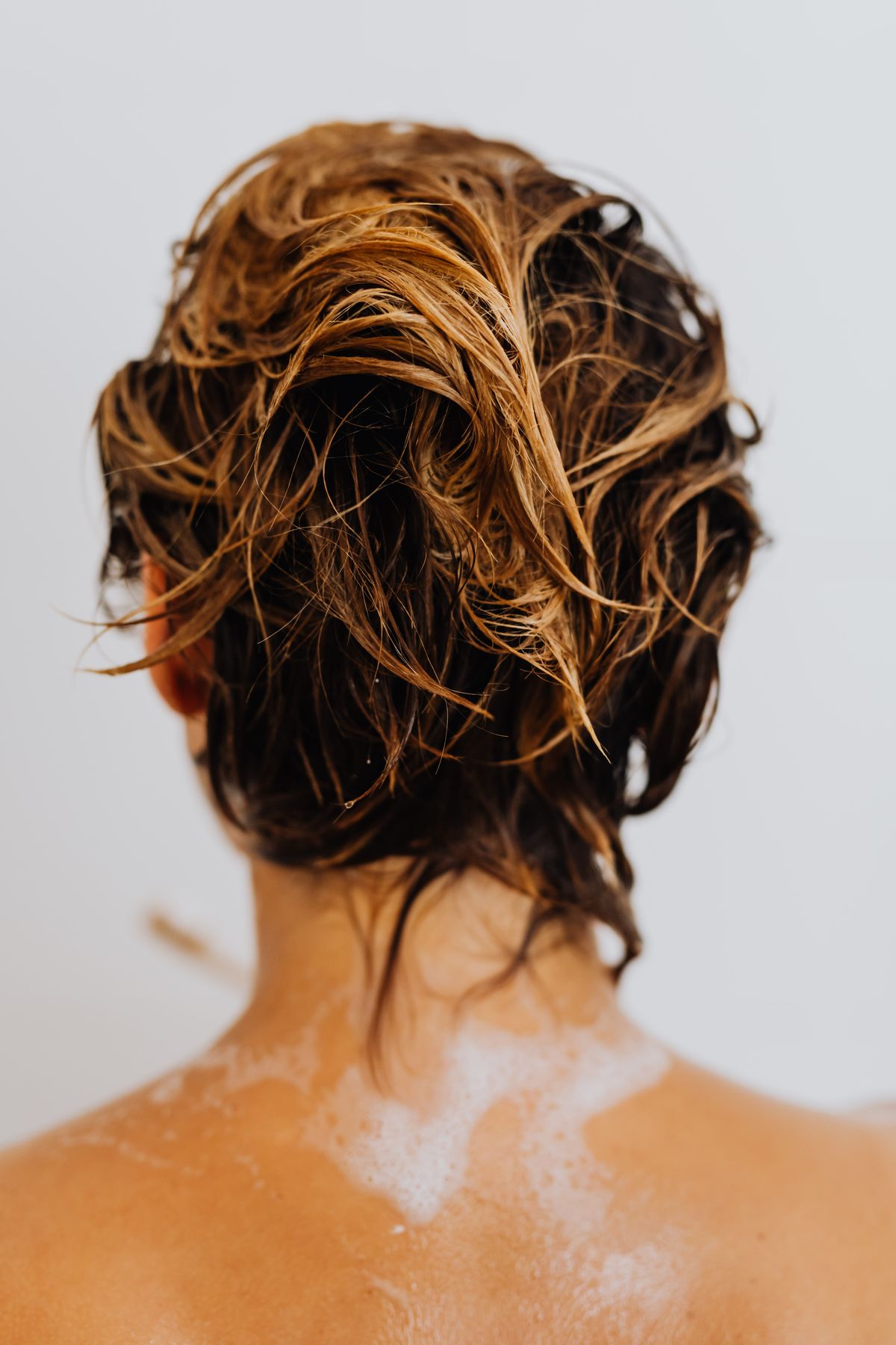 Woman washing her long hair in the shower, the routine most affected by hard water hair buildup