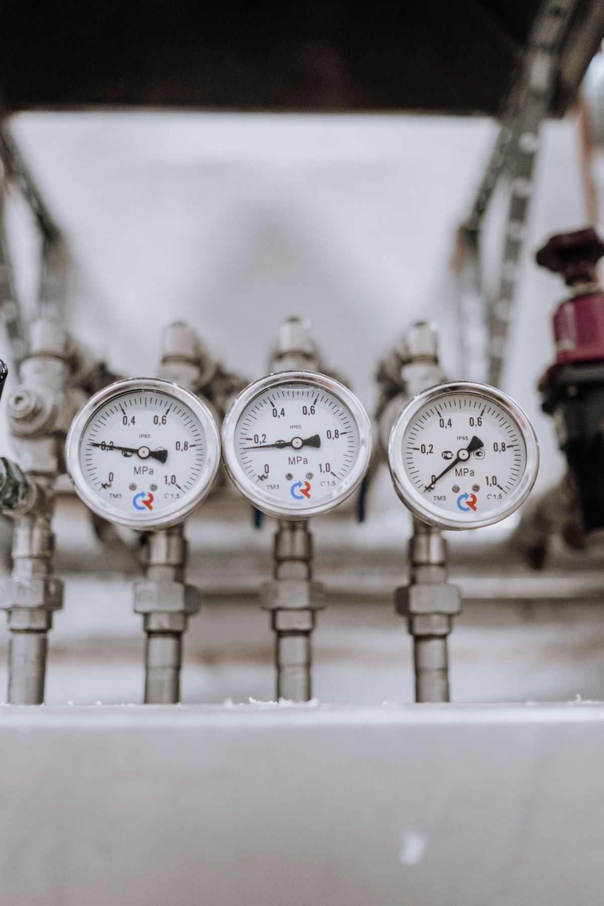 Three industrial pressure gauges mounted on indoor pipework, the measurement that reveals whether a softener has enough pressure to backwash properly