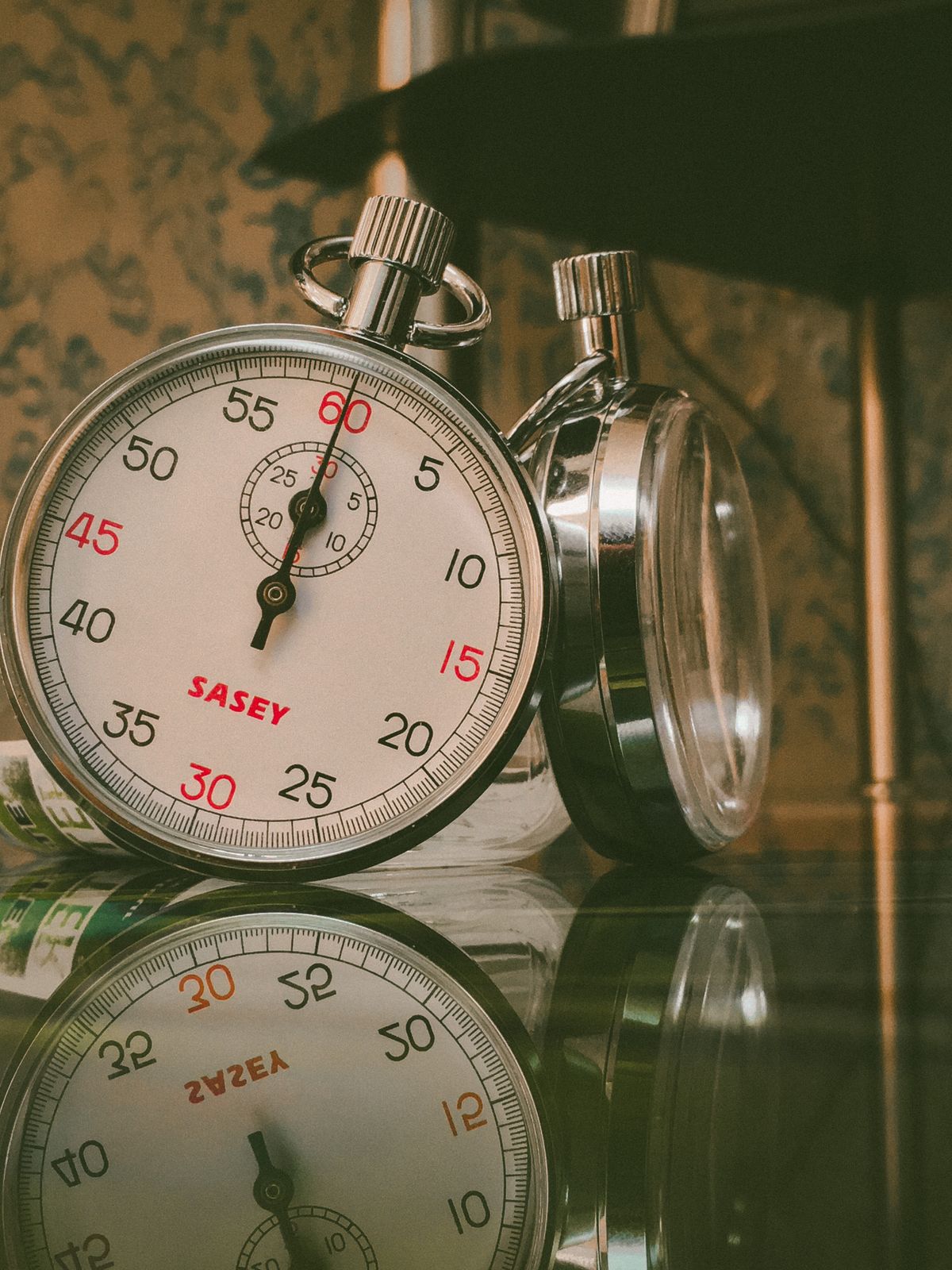 Close-up of a vintage analog stopwatch reflected on a glass surface, the kind of simple timer used to watch a brine tank level fall during a manual regeneration