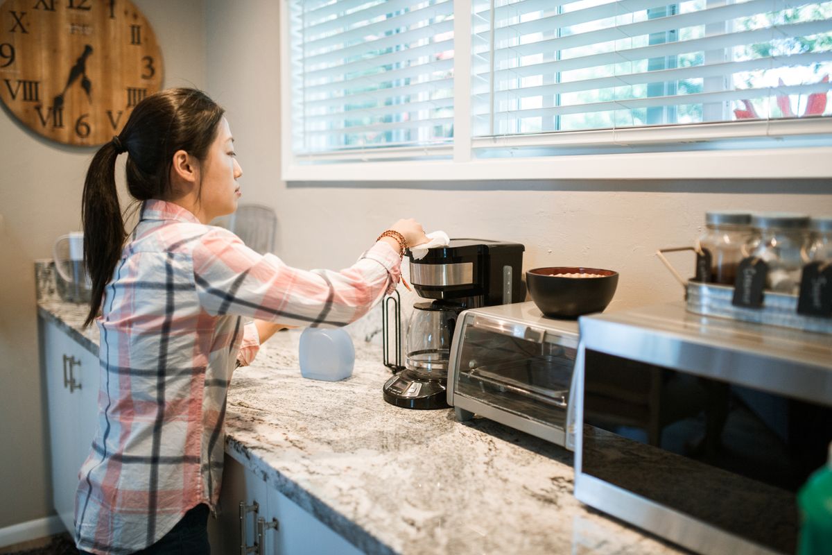Cleaning and maintaining a coffee maker in a bright kitchen