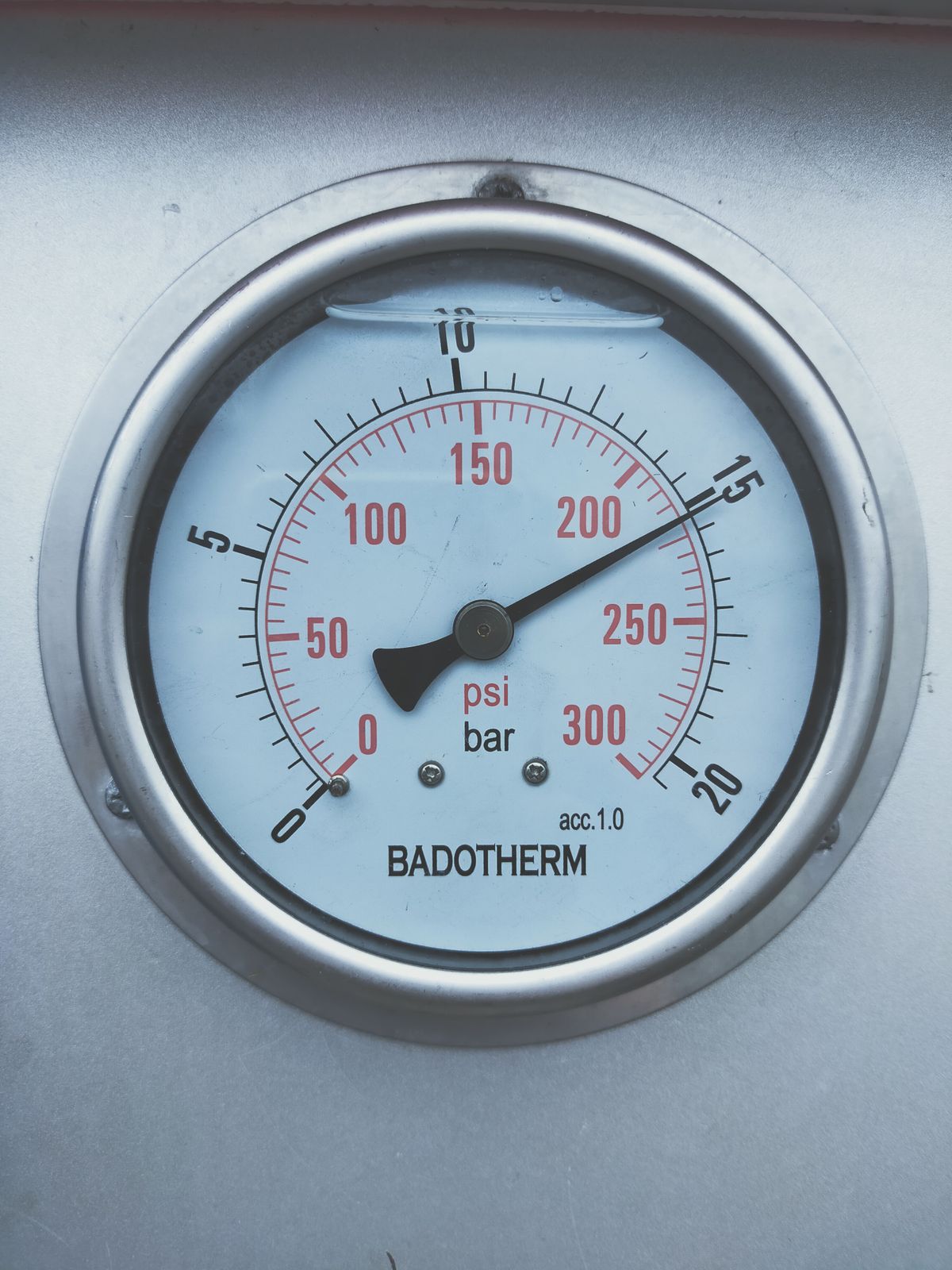 Close-up of a pressure gauge dial reading in psi and bar, the kind of gauge on a well pressure tank tee that marks where softener installation should begin