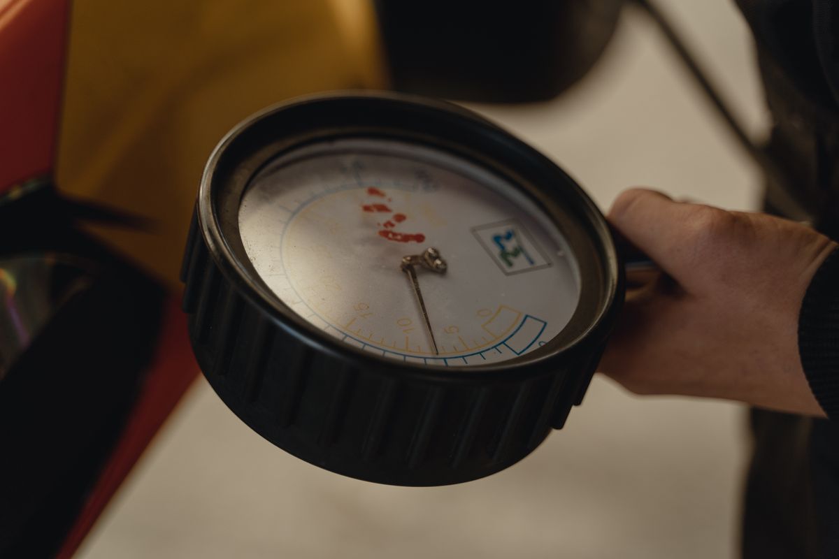 Hand holding a small pressure gauge, the type of tire gauge used to check the air pre-charge on a well pressure tank