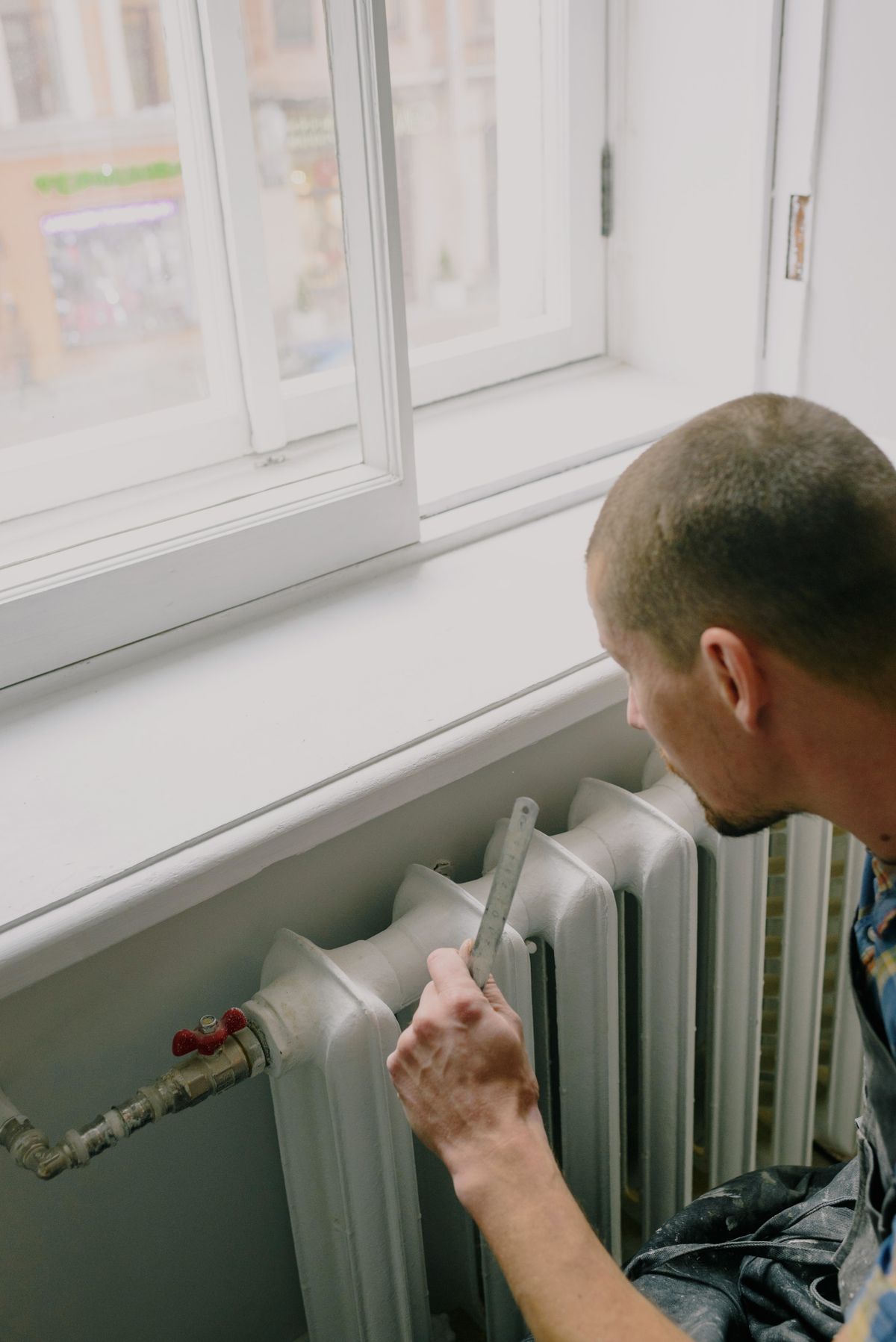 Person measuring near home plumbing and heating pipework, the kind of quick yearly check that keeps a softener bypass valve free to move and its seals supple