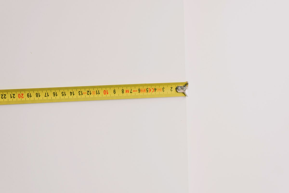 Yellow measuring tape stretched against a plain wall during home renovation work, the kind of simple depth measurement that confirms a salt bridge