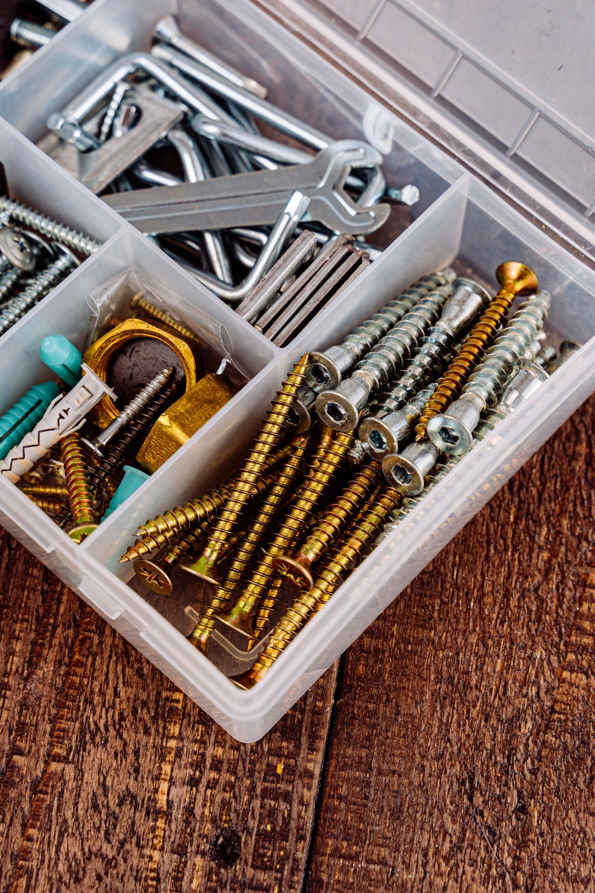 Open toolbox holding assorted screws, wrenches and hand tools on a wooden surface, the kit needed to swap seals or a spacer stack in a softener valve
