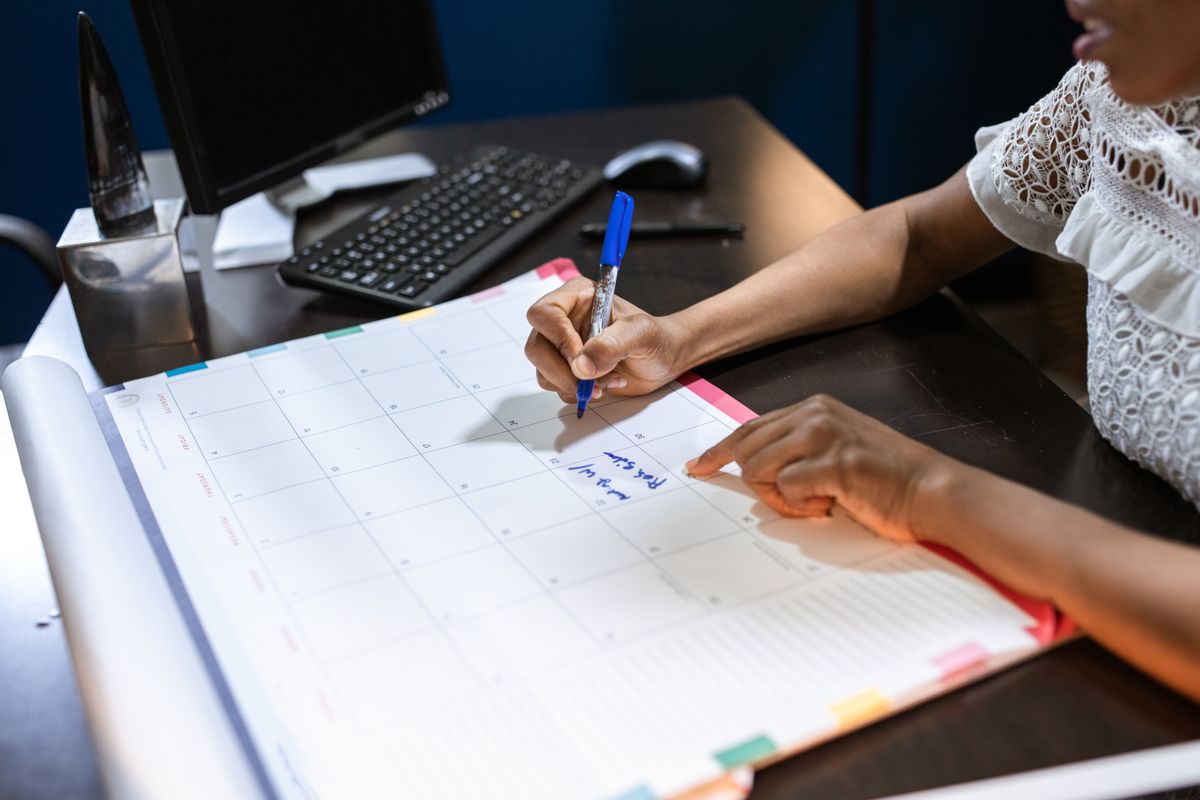 Hand writing entries onto a desk calendar with a pen, the monthly logging habit that turns resin condition into a measurable trend