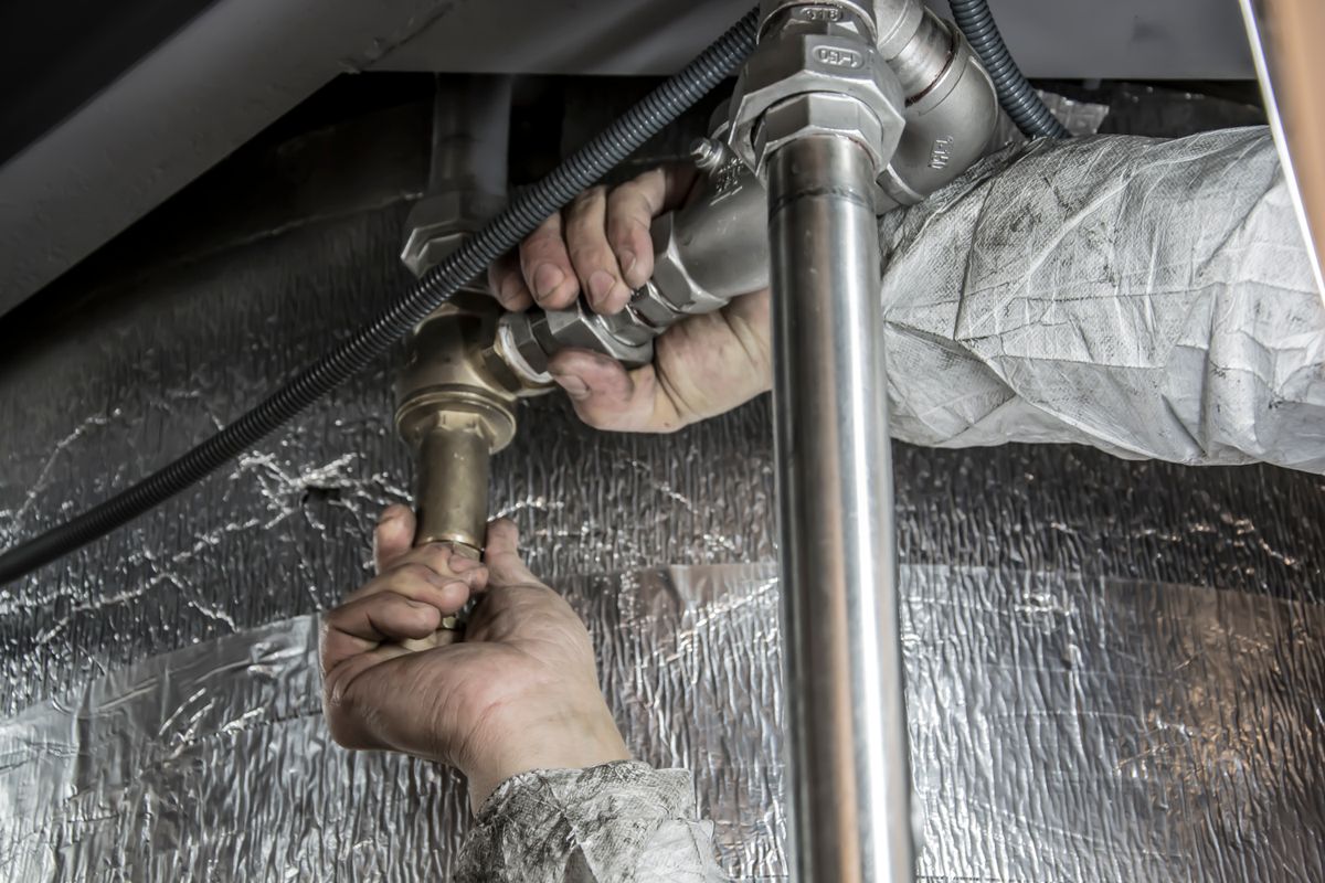 Plumber fitting steel pipework, representing whole-house water softener installation