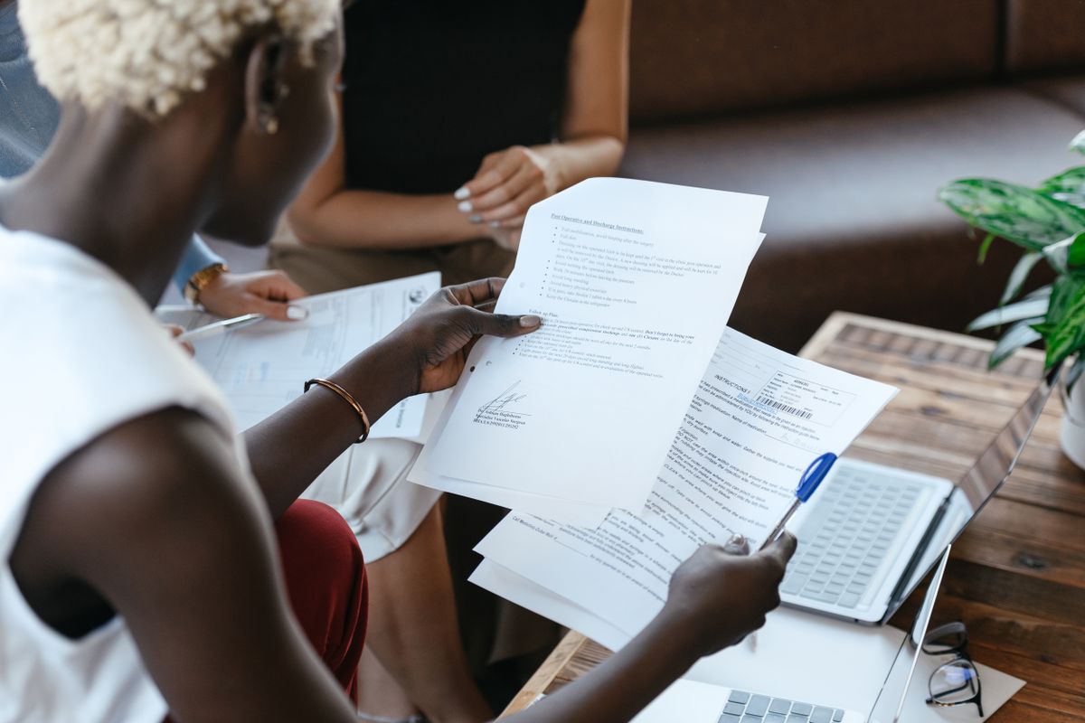 Person holding two printed product documents side by side to compare water softener specifications at a table with a laptop
