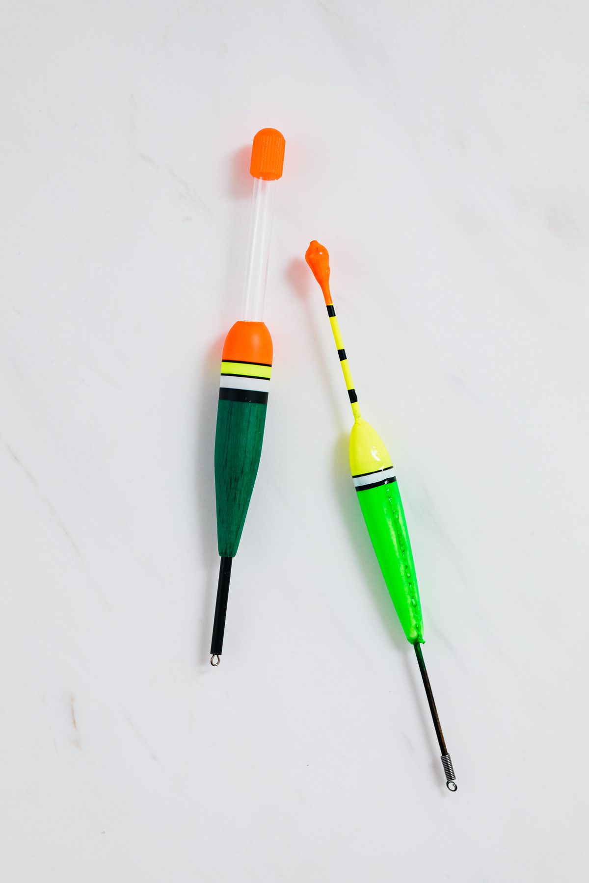 Two brightly coloured fishing floats lying on a white surface, illustrating the buoyant float that rides the water level inside a water softener brine well